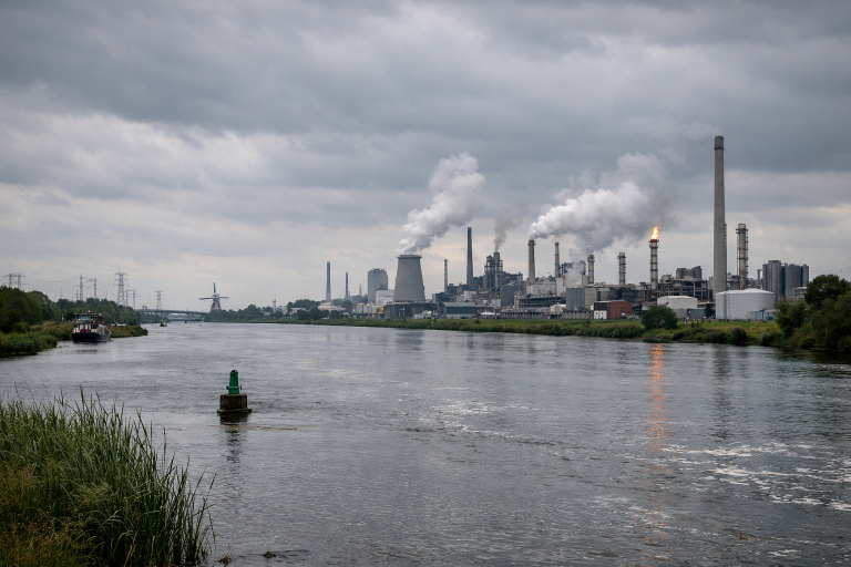 Rivier in Nederland met industrie op de achtergrond onder bewolkte lucht